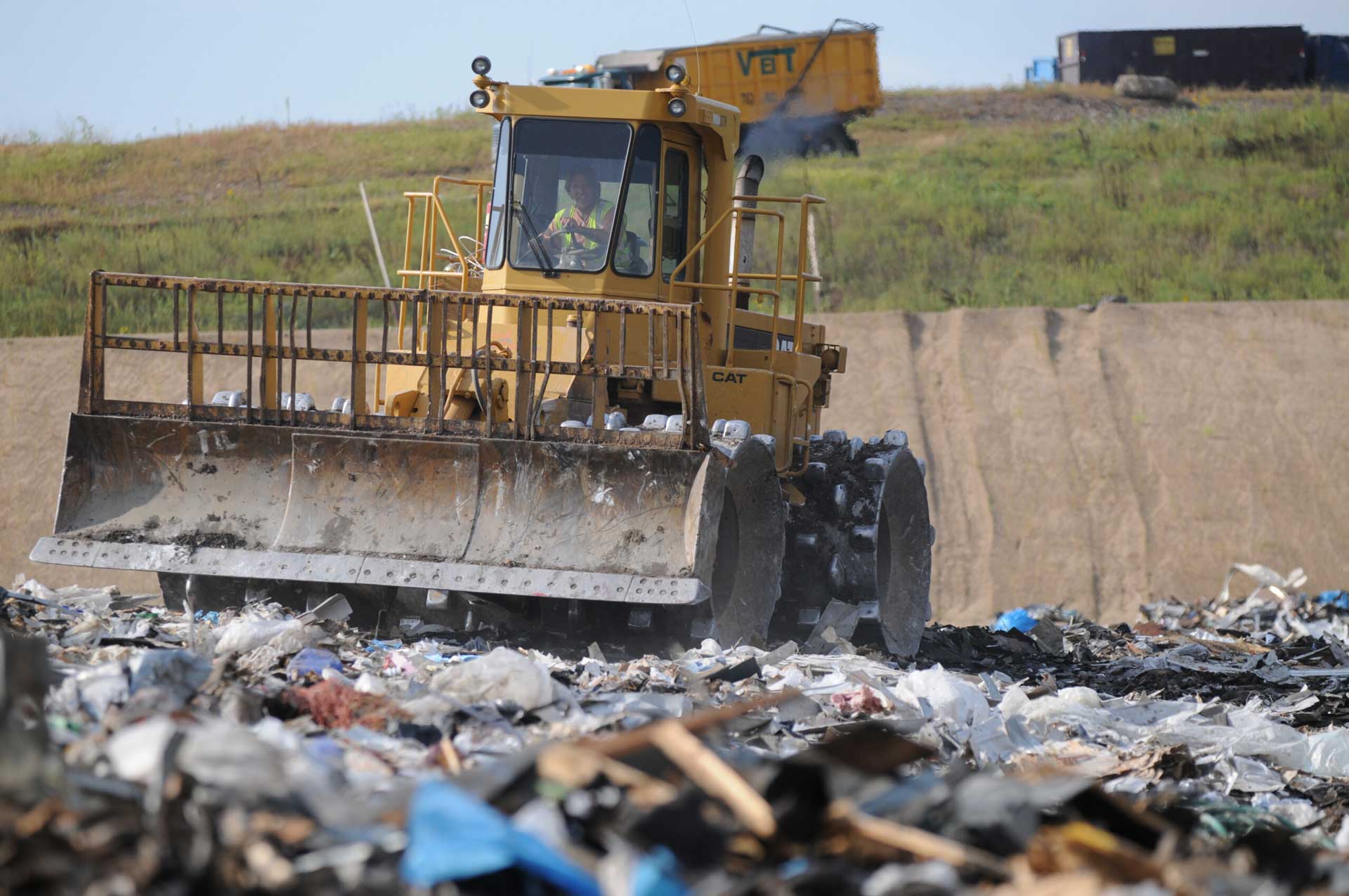 A Dem-Con employee in a bulldozer is managing landfill waste